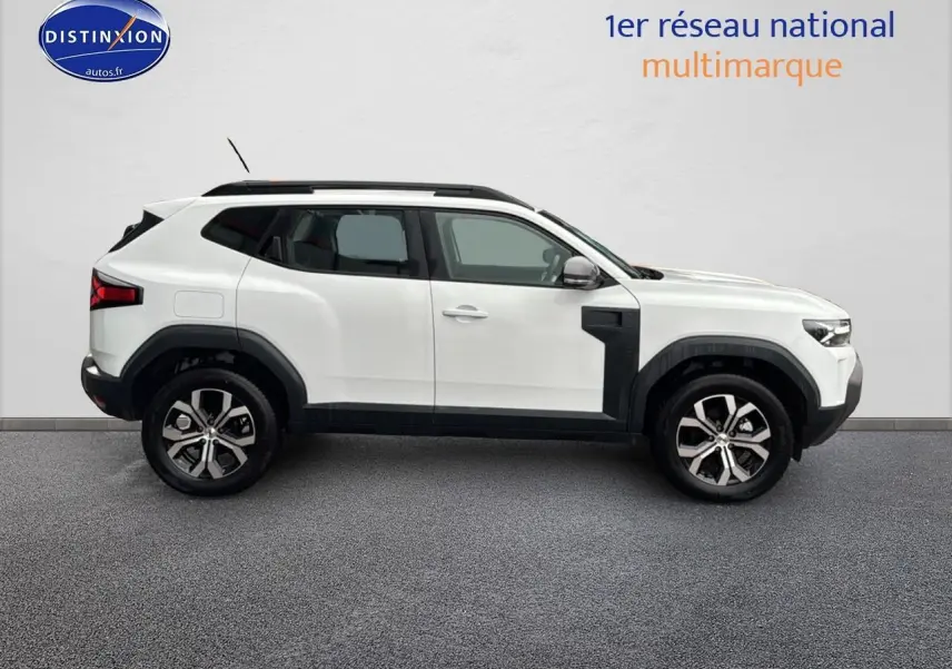 Profil droit du Dacia Duster blanc arctic 2025 avec jantes alu et barres de toit noires visibles.