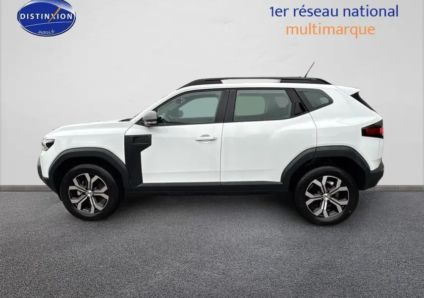 Profil côté gauche du Dacia Duster blanc Arctic 2025 avec jantes alu et barres de toit noires.