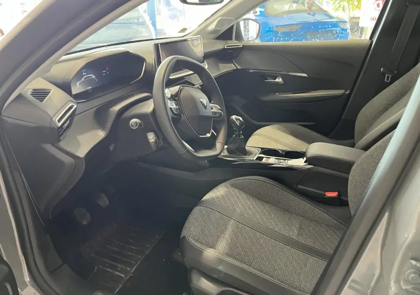 Intérieur avant droit du Peugeot 208 gris clair Selenium, volant compact cuir et sièges tissu gris avec surpiqûres Quartz