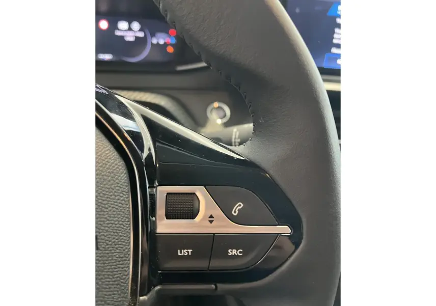 Gros plan sur les commandes multimédia noires et argentées du volant cuir de la Peugeot 208 gris clair Selenium.