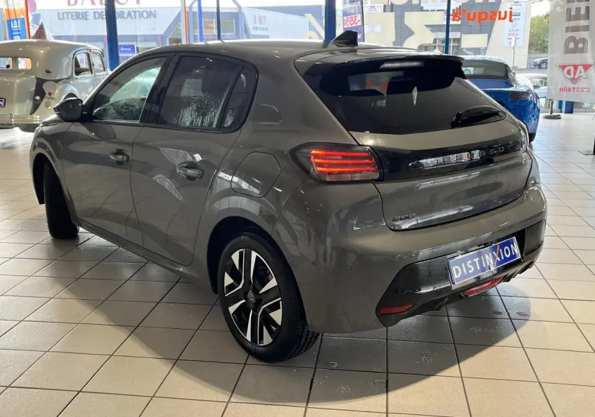PEUGEOT 208 gris clair selenium vue 3/4 arrière droit en showroom avec jantes alliage bi-tons et feux LED allumés