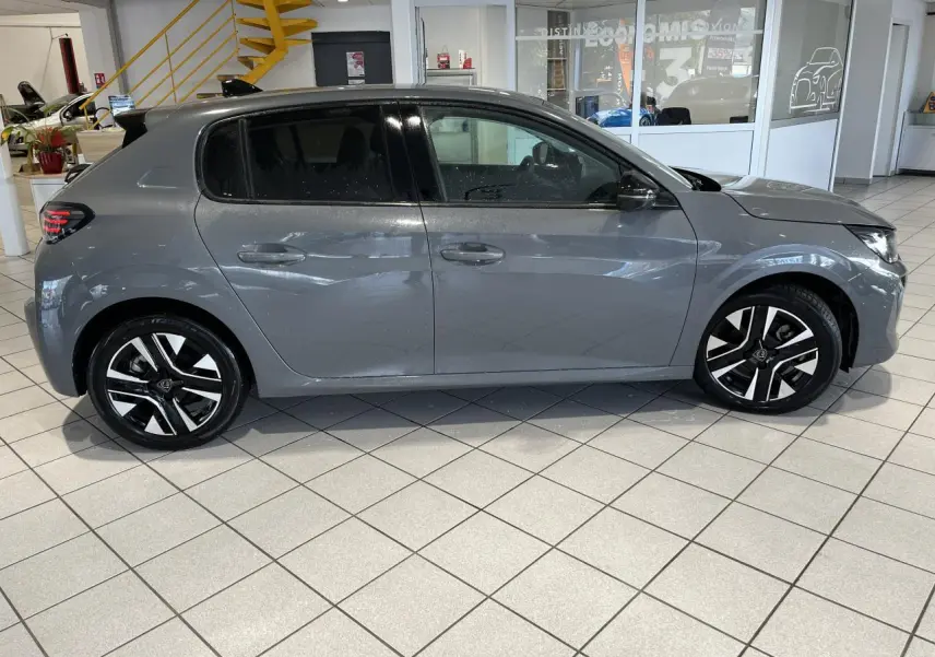 Peugeot 208 gris clair Selenium vue de profil côté gauche en intérieur avec jantes alliage bi-tons et vitres teintées.