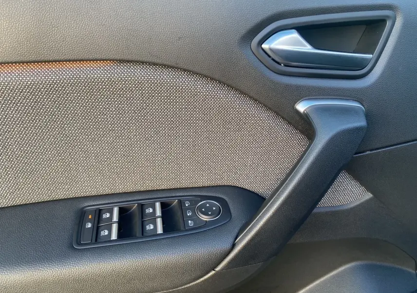 Détail de la porte côté conducteur avec commandes des vitres et poignée en plastique noir dans Renault Symbioz gris Casiopee.