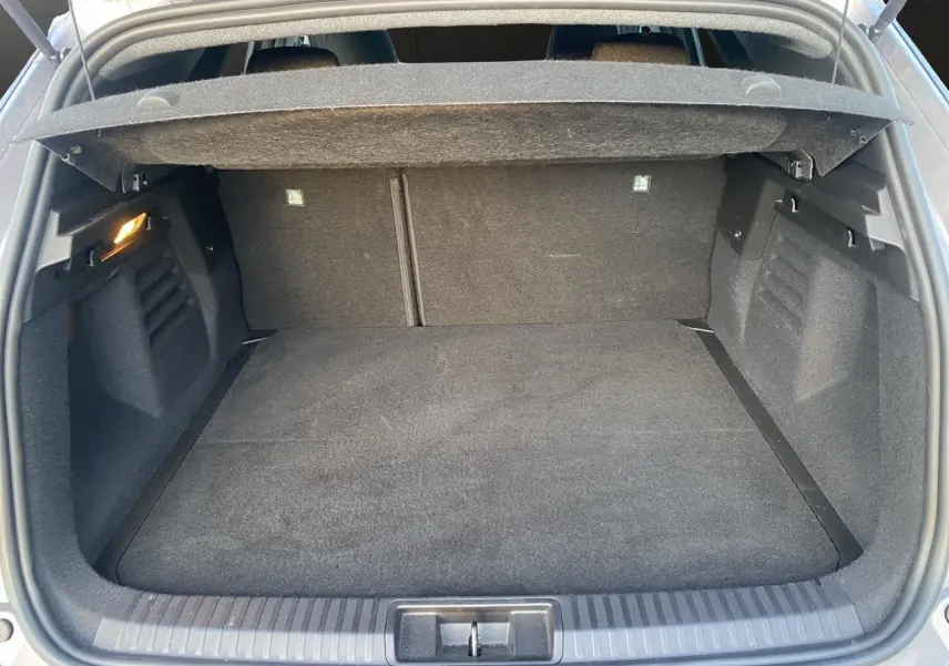 Coffre ouvert vu de l'arrière d'une Renault Symbioz gris Casiopee, montrant l'espace de rangement et la moquette noire.