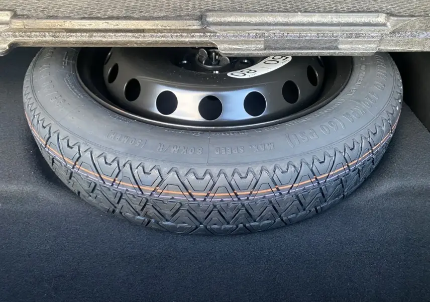 Gros plan sur la roue de secours temporaire noire dans le coffre d'une Renault SYMBIOZ hybride 2025.