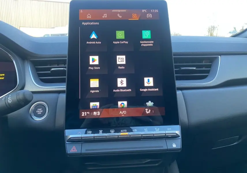 Vue frontale du grand écran tactile central du tableau de bord du Renault Symbioz gris Casiopee, affichant les applications connectées.