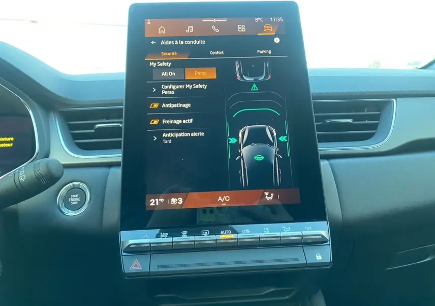 Vue intérieure centrée sur l’écran tactile du tableau de bord du Renault Symbioz gris Casiopee, avec commandes climatisation visibles.