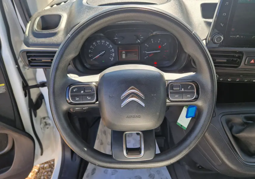 Vue intérieure centrée sur le volant noir du Citroën Berlingo blanc 2020 avec tableau de bord et commandes au volant visibles.
