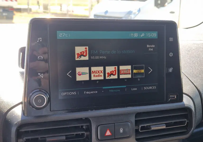 Écran tactile central du tableau de bord du Citroën Berlingo blanc, affichant les stations radio FM.