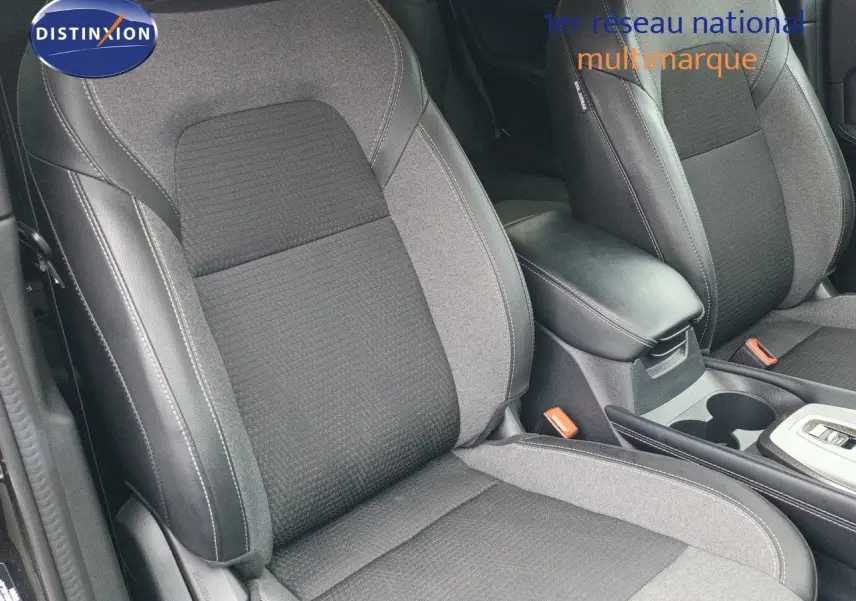 Gros plan sur les sièges avant en tissu noir et gris du Nissan Qashqai e-POWER 2025, avec accoudoir central visible.
