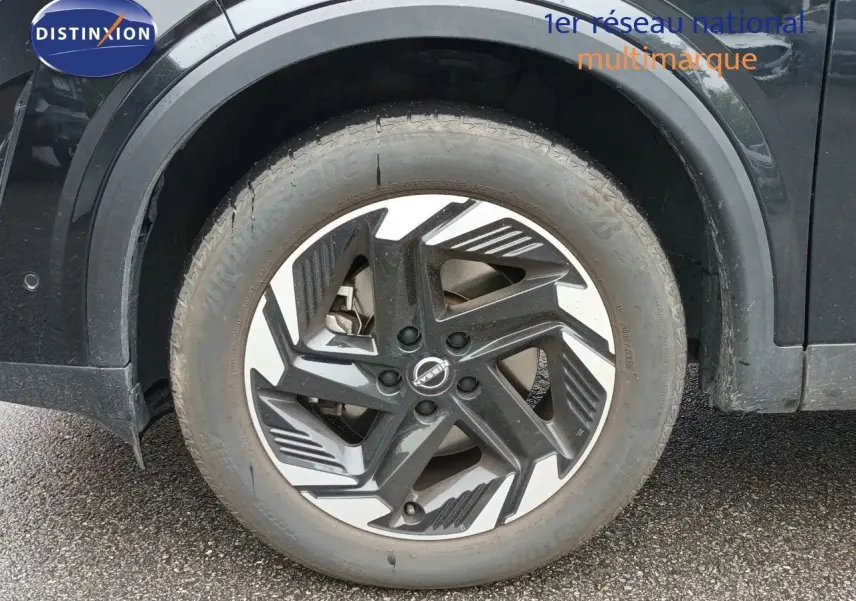 Gros plan sur la roue avant gauche noire Kuro Metal du Nissan Qashqai e-POWER 2025 avec jante design bicolore.