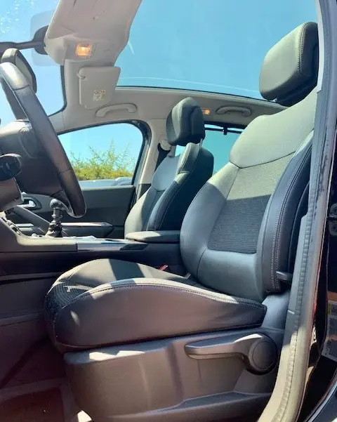 Intérieur du Peugeot 3008 2014 noir, vue côté conducteur montrant les sièges avant en cuir et le toit ouvrant.