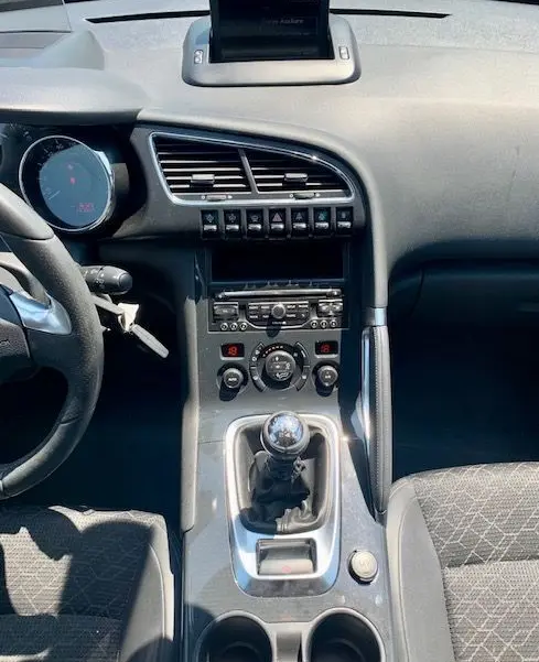 Vue intérieure centrée sur la console centrale et levier de vitesse manuelle du Peugeot 3008 noir de 2014.