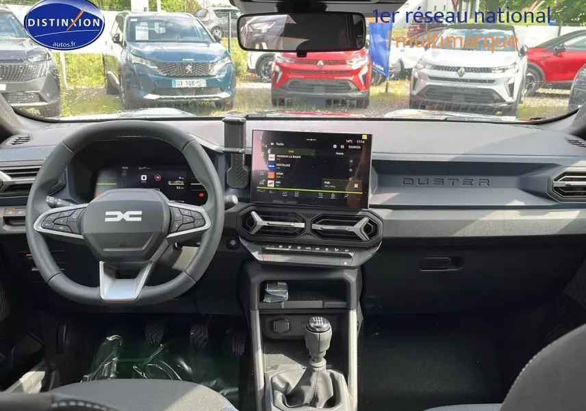 Vue intérieure avant du Dacia Duster 1.0 eco-g 100 Journey 2025, tableau de bord gris avec écran tactile et volant multifonction.