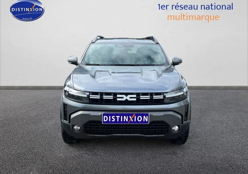 Vue de face du Dacia Duster gris schiste 2025 avec calandre distinctive et phares LED fins allumés.