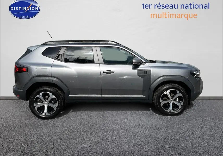 Profil droit du Dacia Duster gris schiste 2025 avec jantes alu et barres de toit visibles.