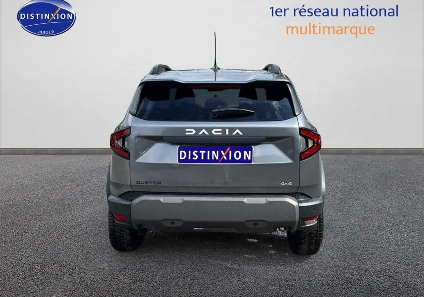 Vue arrière du Dacia Duster gris schiste 2025 avec logo DACIA lumineux et plaques Distinxion visibles.