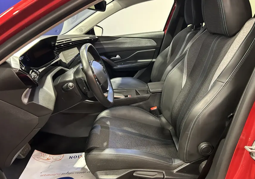 Vue intérieure côté conducteur de la Peugeot 308 rouge 2024, mettant en valeur les sièges en cuir et le tableau de bord moderne.