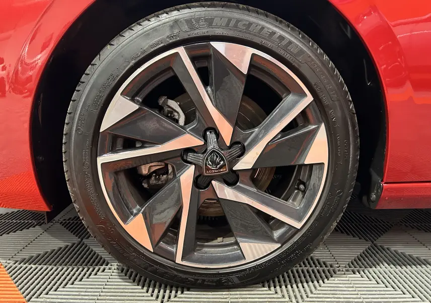 Gros plan sur la jante avant droite de la Peugeot 308 rouge 2024, avec un design moderne et pneus Michelin visibles.