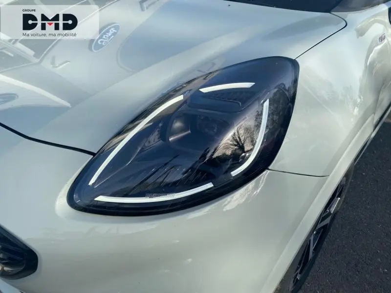 Gros plan sur le phare avant droit d'un Ford Puma gris clair avec jante alu visible en arrière-plan.