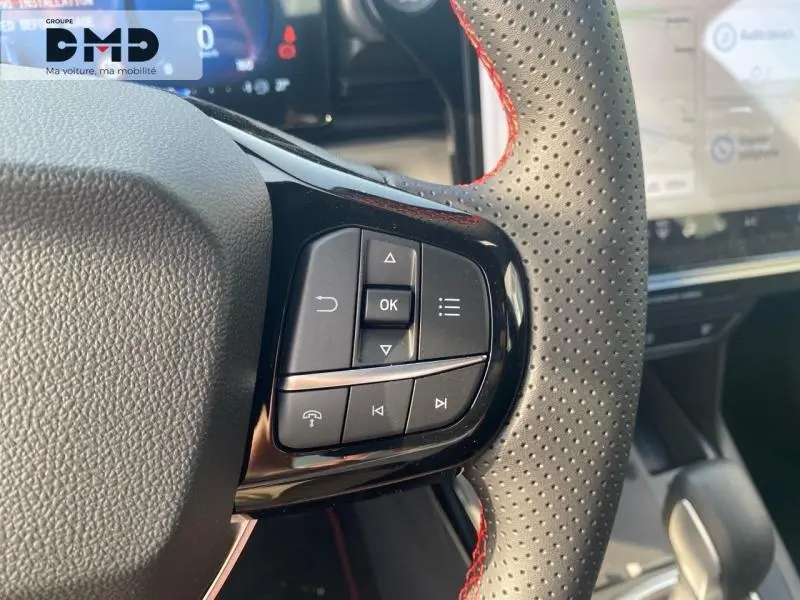 Gros plan sur les commandes multifonctions du volant perforé avec surpiqûres rouges du Ford Puma gris Cactus.