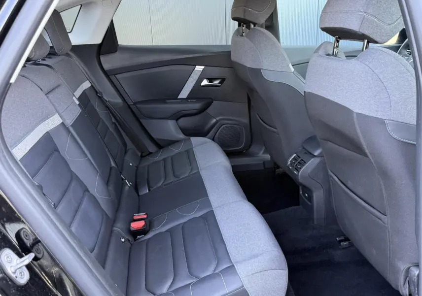 Vue intérieure arrière côté gauche de la Citroën C4 X 2024 noir Perla avec sièges bicolores tissu et cuir.