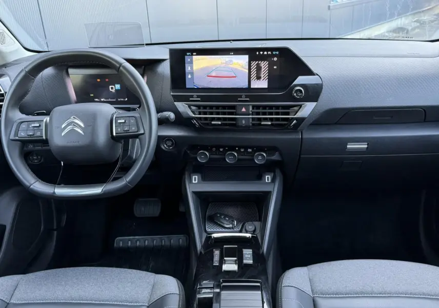 Vue intérieure avant du Citroën C4 X 2024 noir Perla, tableau de bord avec écran tactile et caméra de recul affichée.