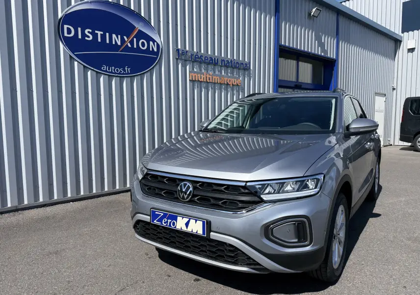 Volkswagen T-Roc gris pyrite en 3/4 avant droit, avec calandre noire et phares LED distinctifs.