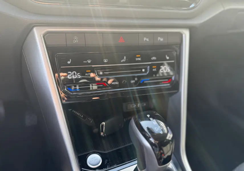 Gros plan sur la console centrale du Volkswagen T-ROC 2025, montrant la climatisation digitale et le levier de boîte automatique.