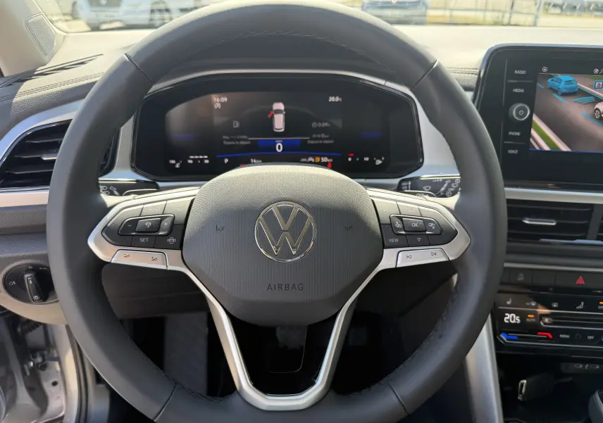 Vue rapprochée du volant noir du Volkswagen T-Roc 2025 avec tableau de bord digital et écran central tactile.