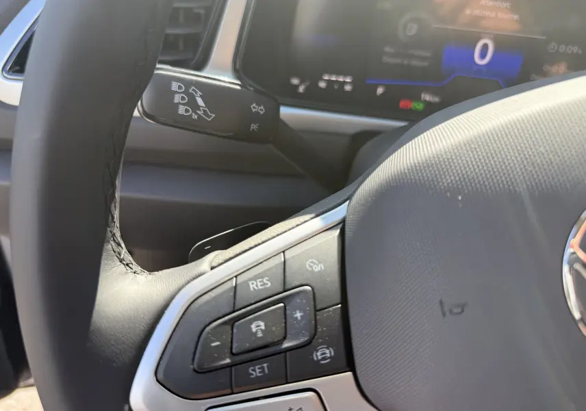 Gros plan sur le volant et les commandes du régulateur de vitesse du Volkswagen T-Roc 2025, intérieur noir.