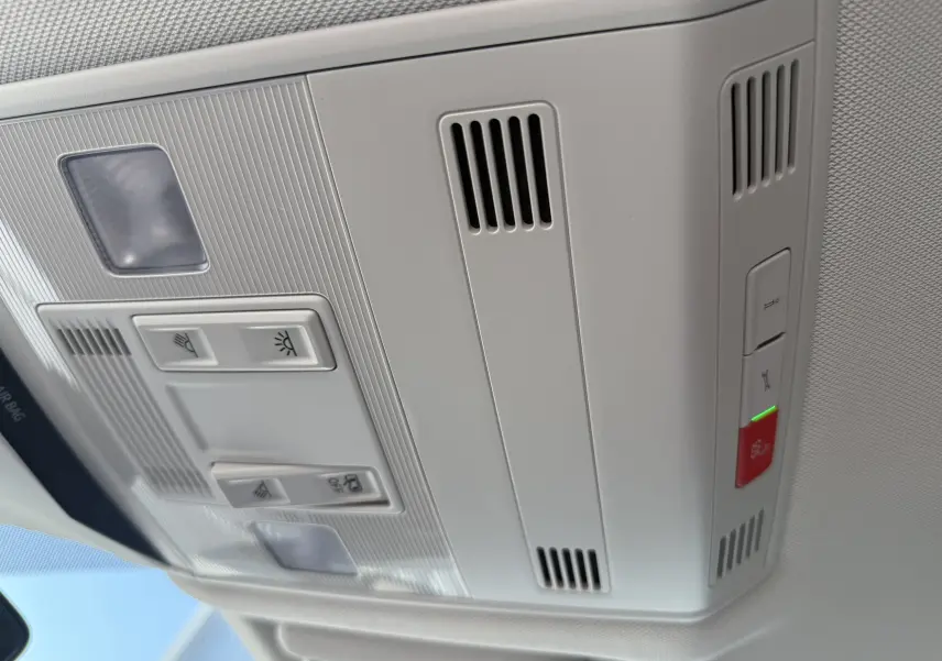 Vue en gros plan du plafonnier gris clair du Volkswagen T-Roc 1.5 TSI 150 DSG7 avec commandes d'éclairage et bouton d'alerte rouge.