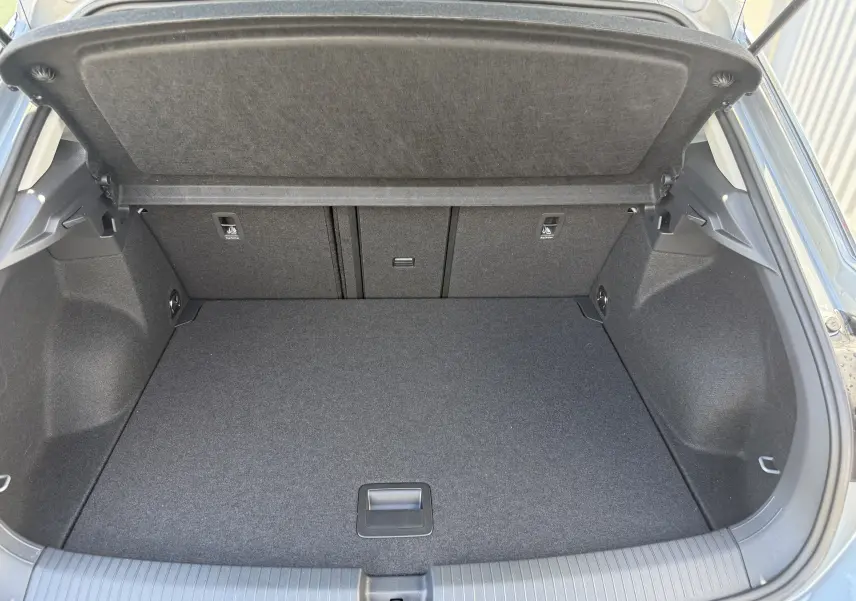 Coffre ouvert du Volkswagen T-Roc gris pyrite 2025, montrant un espace de chargement propre et bien aménagé.