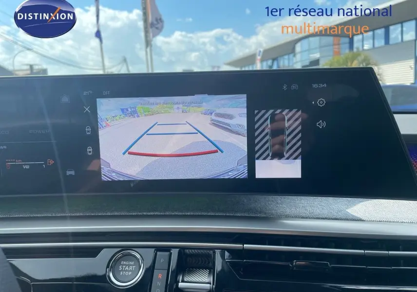 Vue intérieure du tableau de bord du Peugeot 5008 Hybrid noir perle, avec écran affichant la caméra de recul et commandes centrales.