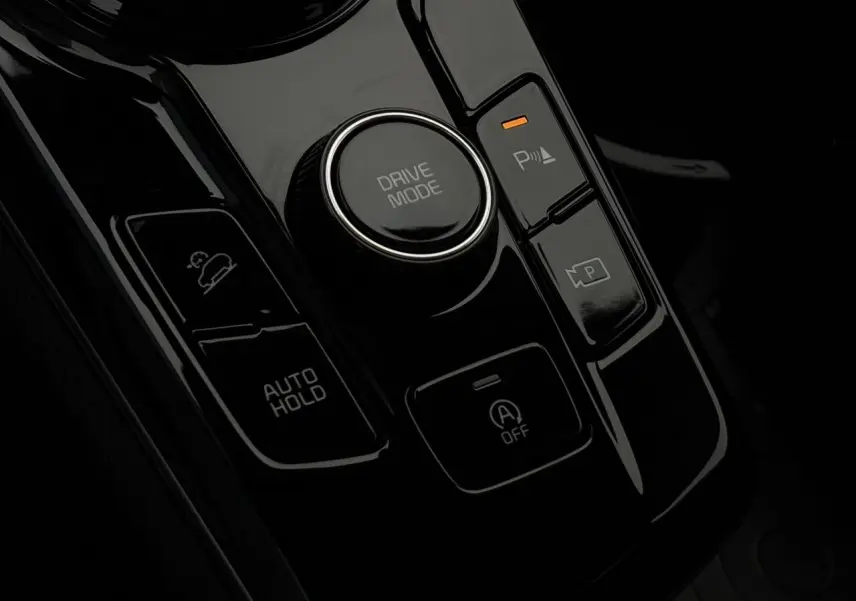 Gros plan sur la console centrale noire du Kia Sportage 2025 avec bouton Drive Mode et commandes Auto Hold.