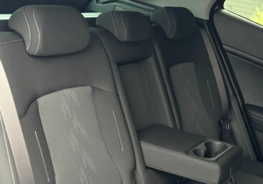 Vue latérale intérieure des sièges arrière noirs avec accoudoir central et porte-gobelets du Kia Sportage 2025.