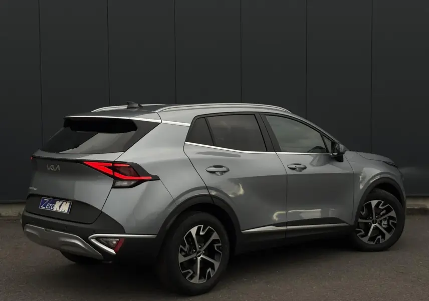 KIA SPORTAGE gris perle vu en 3/4 arrière droit, avec jantes alliage 18 pouces et feux arrière LED distinctifs.