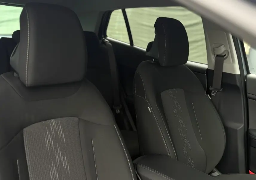 Gros plan sur les sièges avant noirs du Kia Sportage 2025 avec coutures contrastées et accoudoir central.