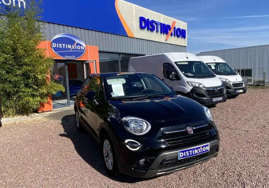 Fiat 500X noir vue 3/4 avant droit, avec jantes alliage 16 pouces, stationnée devant un concessionnaire Distinxion.