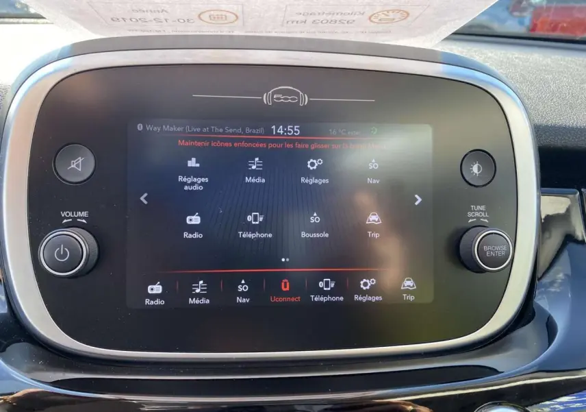 Écran tactile central de la Fiat 500X noir, affichant le menu multimédia avec commandes autour en vue frontale rapprochée.