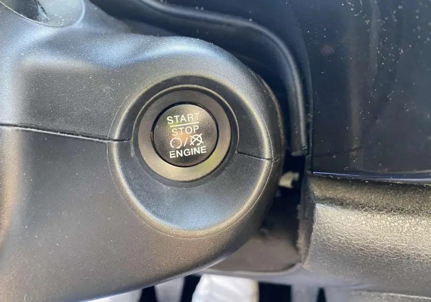 Bouton start/stop moteur en gros plan sur le tableau de bord du Fiat 500X noir de 2019.