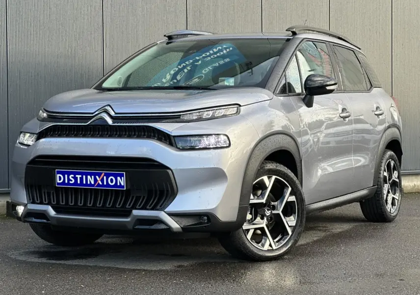 Citroën C3 Aircross gris Artense vue 3/4 avant droit, avec jantes alliage 17'' et barres de toit noires.