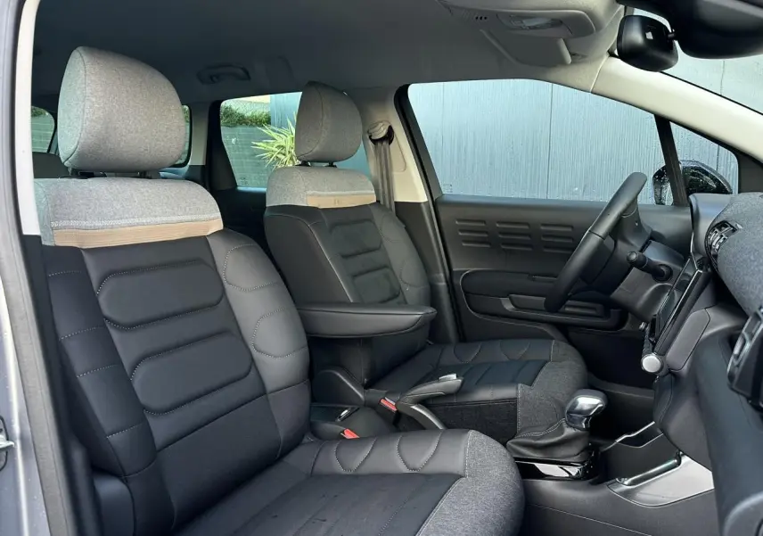 Vue intérieure côté droit de la Citroën C3 Aircross 2024, sièges avant en toile gris et noir avec accoudoir central.