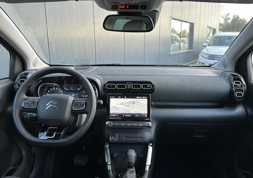 Vue intérieure frontale du tableau de bord et volant noir du Citroën C3 Aircross 2024 avec écran tactile GPS allumé.