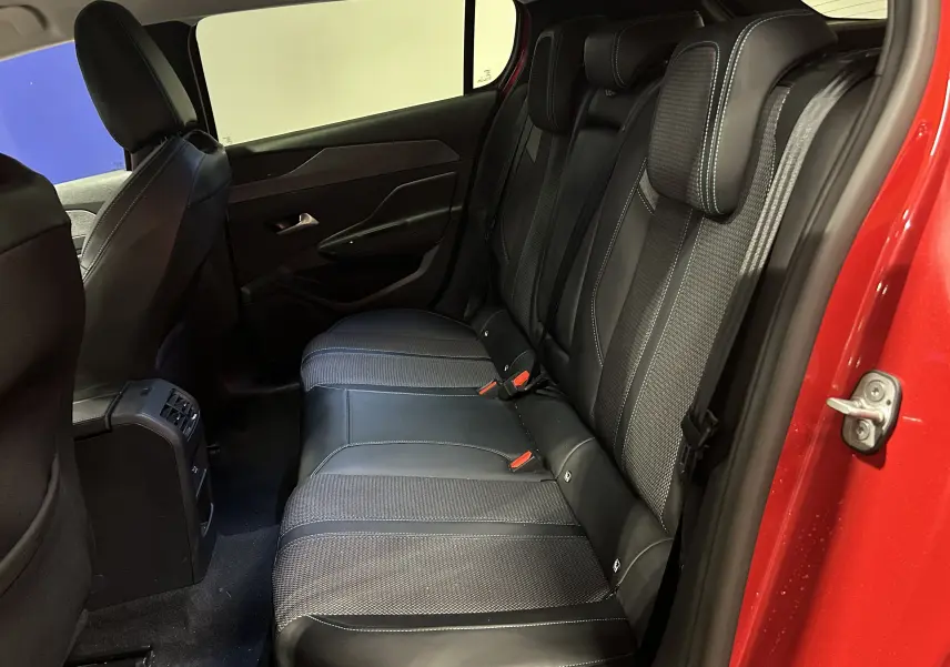 Vue intérieure côté droit des sièges arrière en cuir noir avec surpiqûres bleues, porte rouge ouverte de la Peugeot 308 2024.