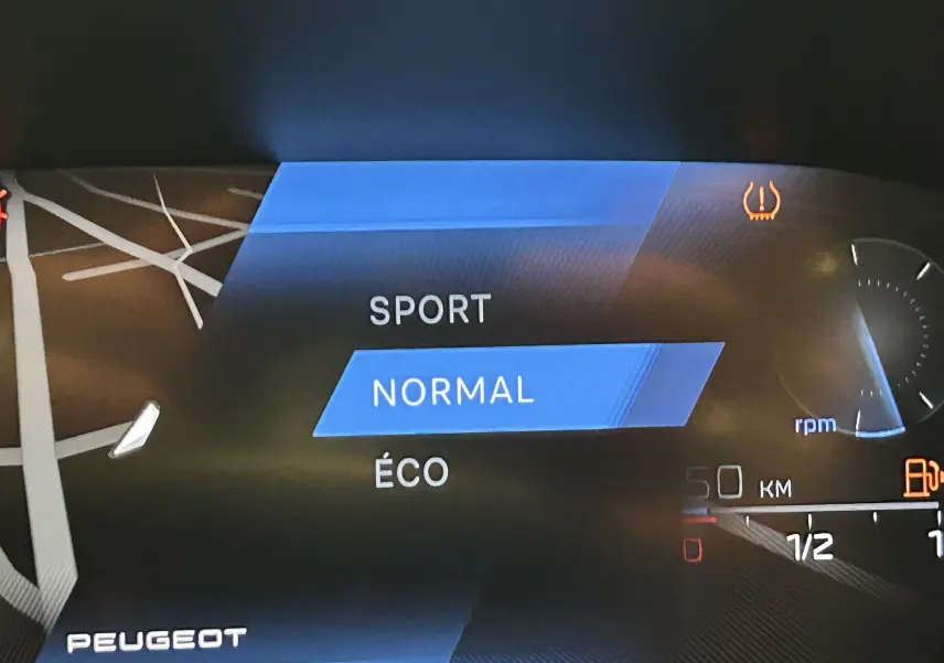Affichage numérique du tableau de bord Peugeot 308 rouge 2024, mode de conduite normal sélectionné, vue intérieure rapprochée.