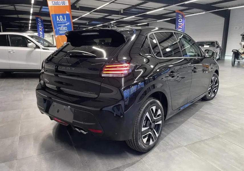 Vue 3/4 arrière droite d'une Peugeot 208 noire métallisée avec feux arrière allumés en showroom intérieur.