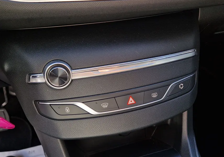 Détail du tableau de bord noir de la Peugeot 308 SW 2021, avec commandes de verrouillage, dégivrage et alerte hazard visibles.