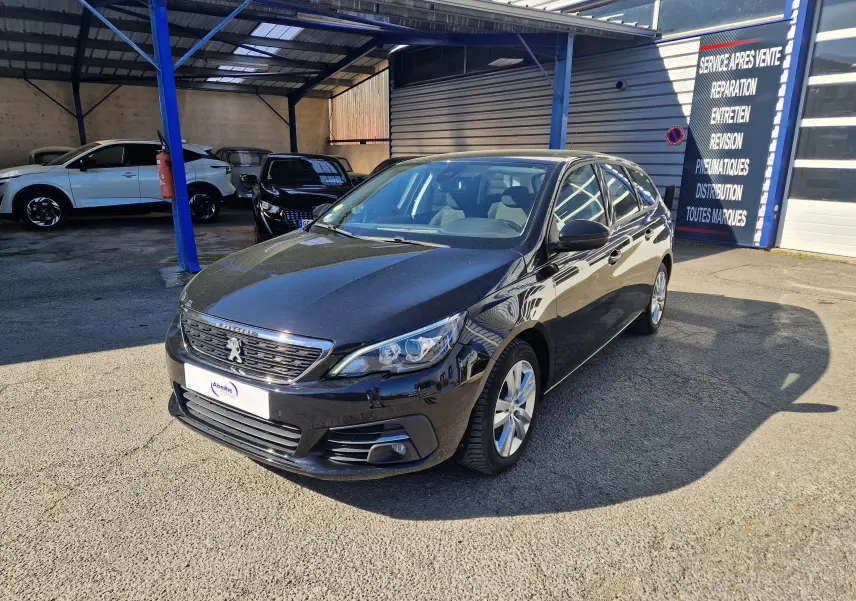 Peugeot 308 SW noire vue en 3/4 avant droit, avec calandre chromée et jantes alliage 16 pouces visibles.