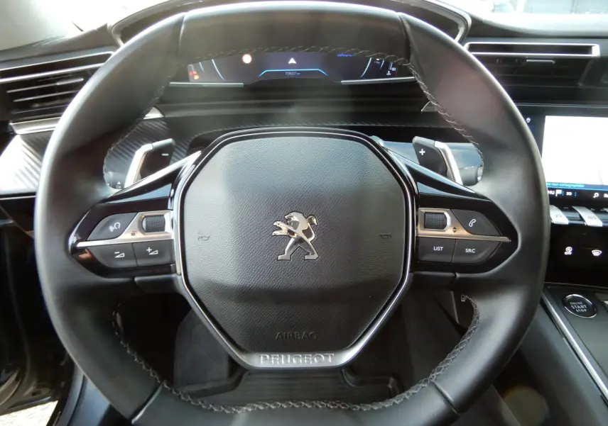 Volant en cuir noir de Peugeot 508 SW 2020 avec commandes intégrées et tableau de bord numérique en arrière-plan.